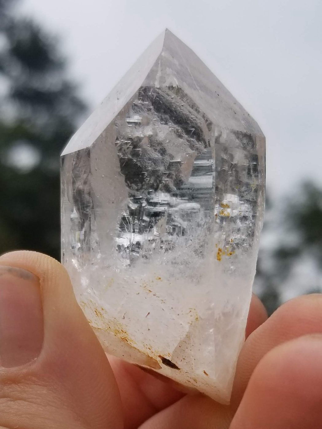 A clear quartz point held up against the sky
