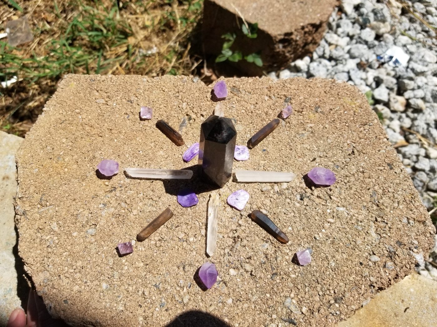 A crystal grid with smoky quartz and amethyst arranged outdoors