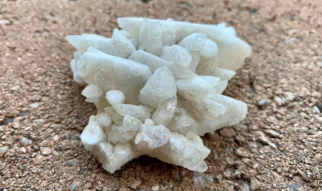 A white crystal cluster specimen resting on stone